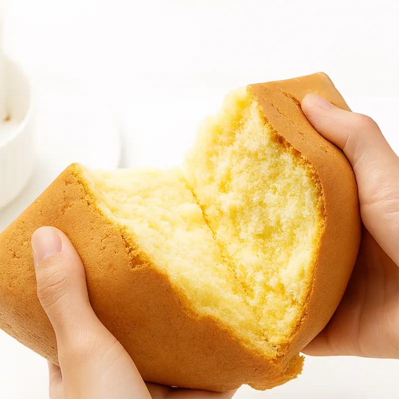 Hands breaking soft sponge cake made with premium organic wheat, showcasing fluffy texture and moist crumb—ideal for high-quality baking applications