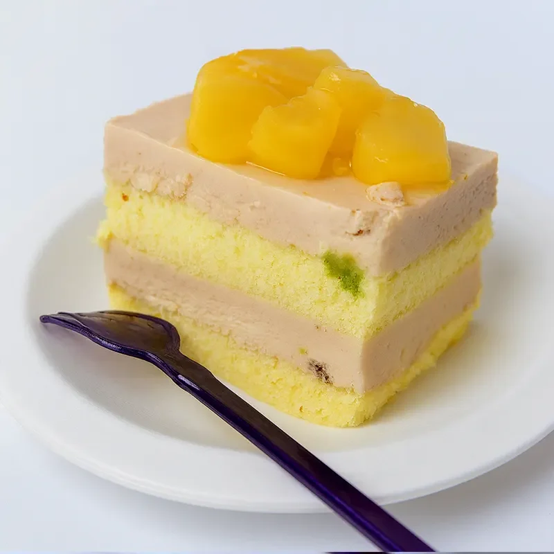 Slice of mango-topped sponge cake made with mineral-free cake premix, showcasing soft texture and even layers—ideal for professional baking applications