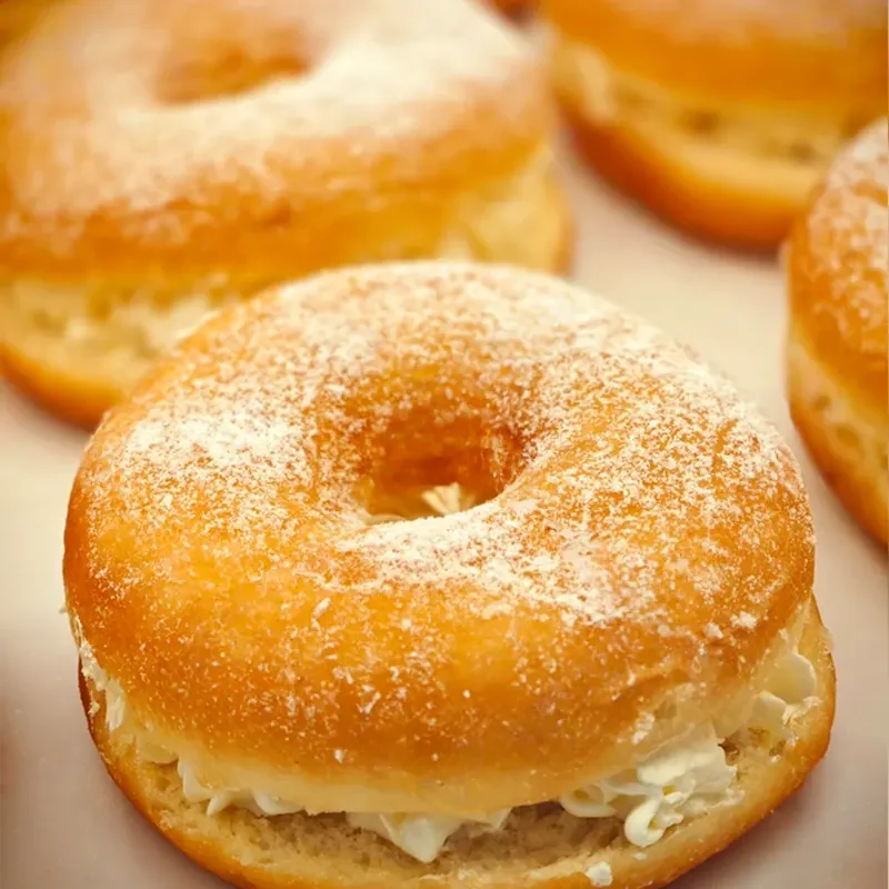 Custard cream-filled donuts dusted with powdered sugar—ideal dessert for custard powder lovers and bakery applications