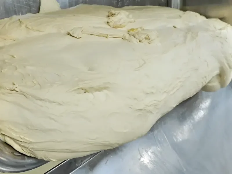 Fermented dough resting in industrial baking equipment, showing optimal yeast activity for high-output food manufacturing. Suitable for continuous production and consistent batch quality.
